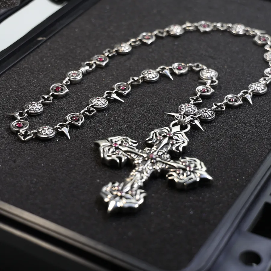 A silver cross pendant and its chain in a fitted case