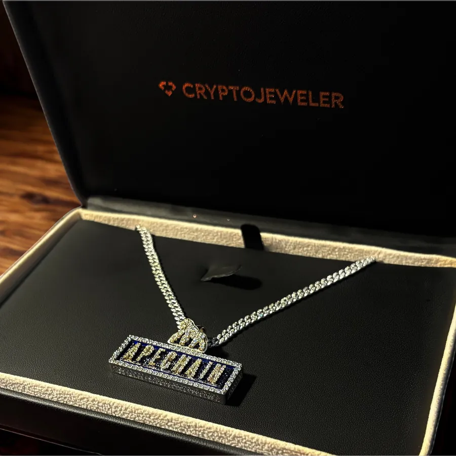 A pavé ApeChain nameplate pendant and its chain, in an open CryptoJeweler presentation box